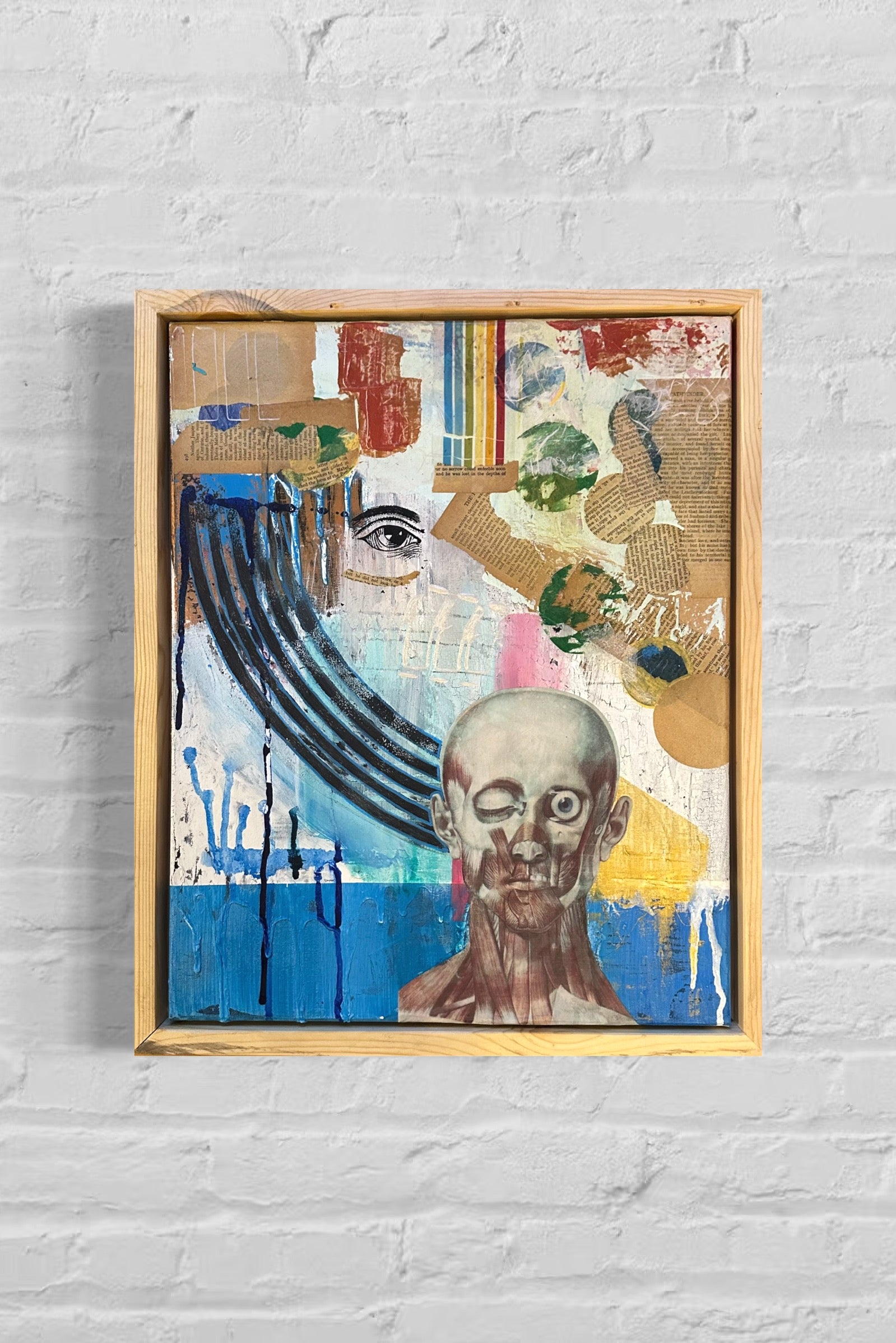 Framed abstract artwork with a portrait on a white brick wall