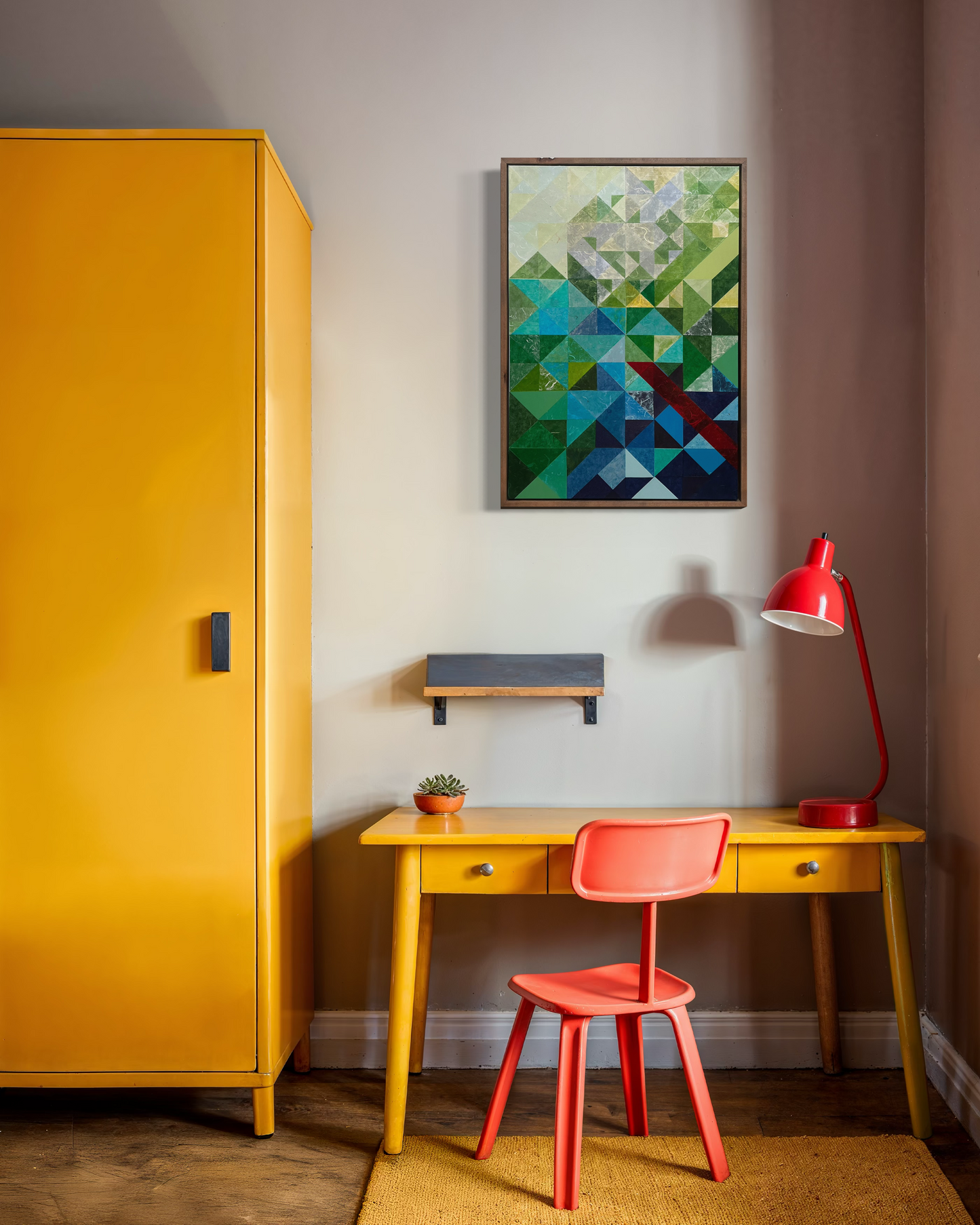 Yellow desk with red chair and lamp, geometric art on wall